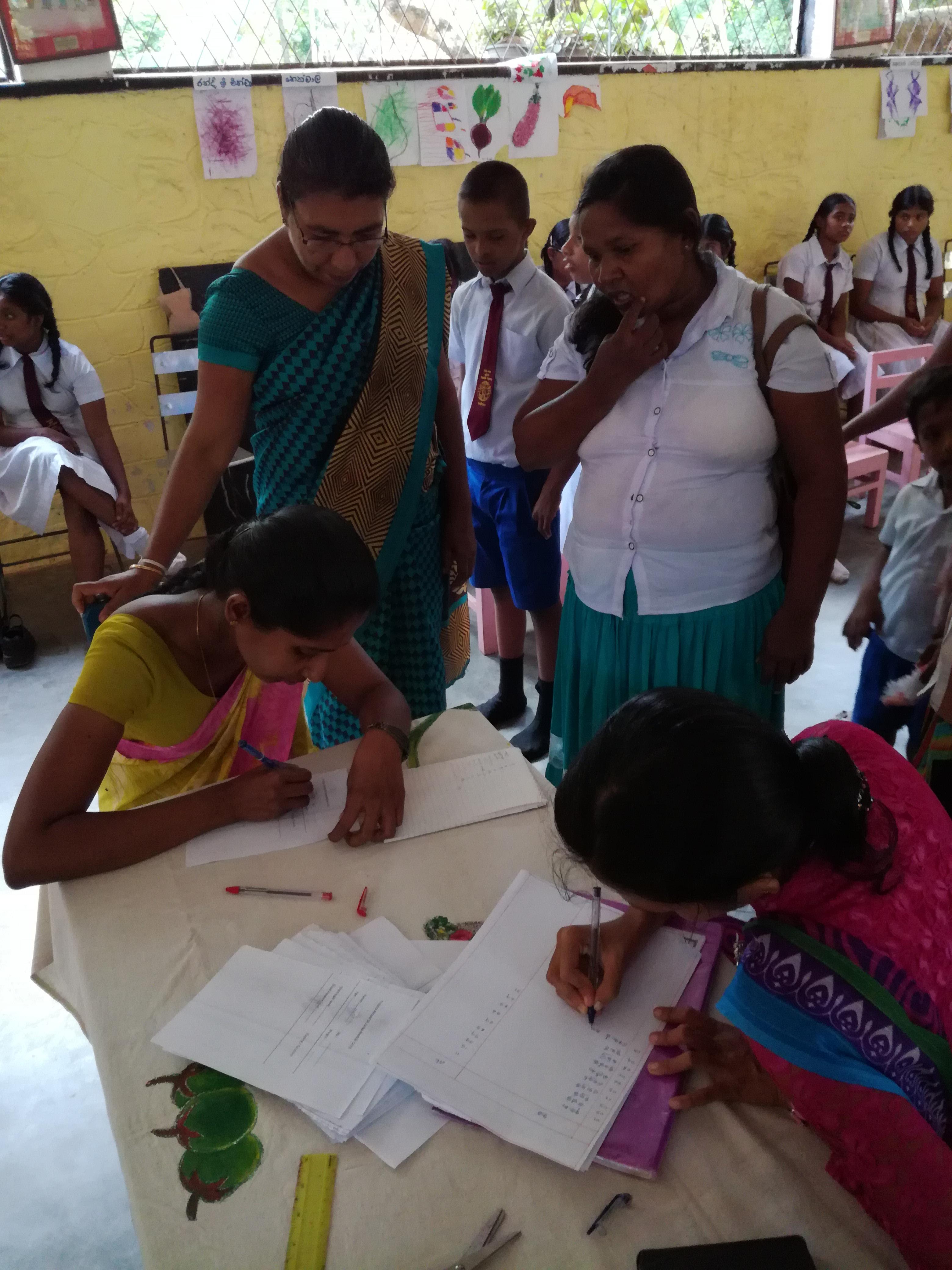 A group of local women fill in their details for Midwifery interns during a community outreach in Sri Lanka. Local Sri Lankan women provide their details for medical staff at an outreach organised and run by Projects Abroad.
